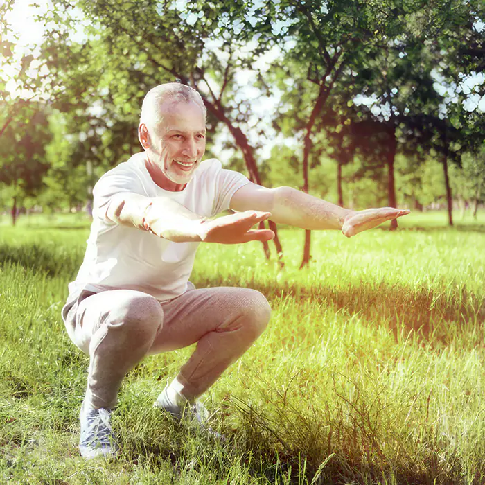 Älterer Mann macht Kniebeugen im Freien.